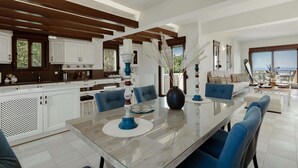 A modern kitchen with white cabinets, a large dining table, and blue chairs. - New beautiful artistic  villa! 1km to the beach! (Gerani)