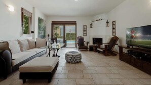 A modern living room with a sofa, ottoman, TV, and a fireplace. - New beautiful artistic  villa! 1km to the beach! (Gerani)