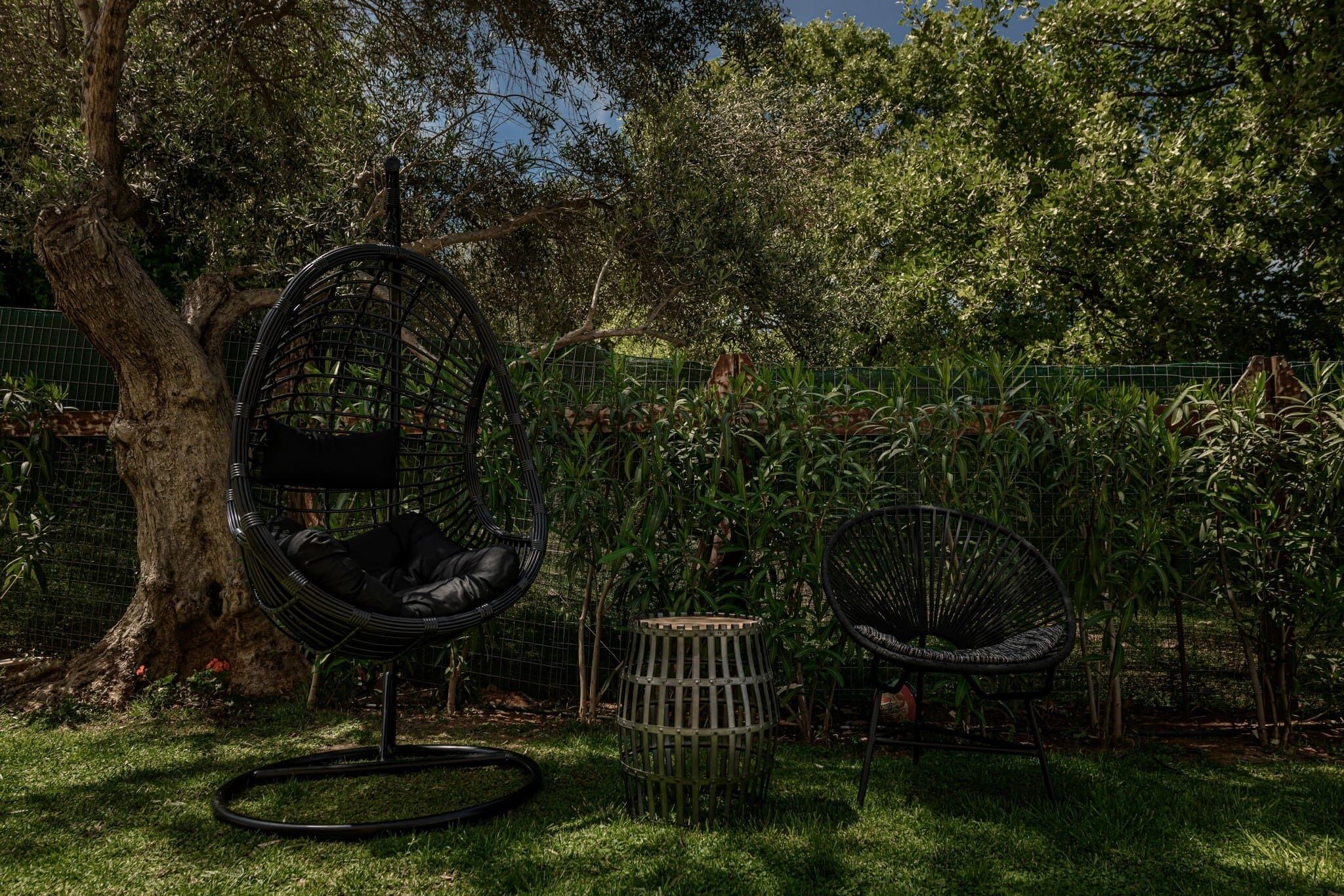 A garden area with a tree, a hanging chair, and a small round table.