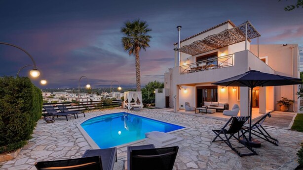A modern two-story house with a swimming pool, outdoor seating, and a view of the city at dusk. - New beautiful artistic  villa! 1km to the beach! (Gerani)