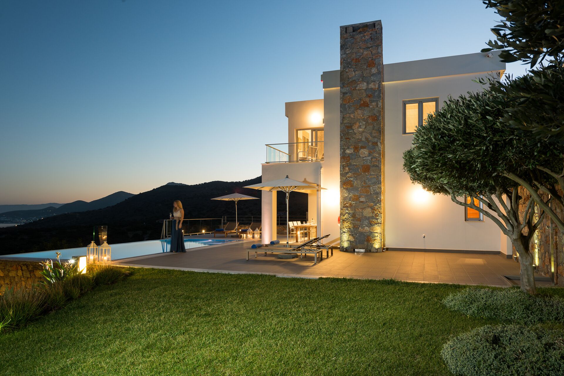 Uma casa moderna de dois andares, com piscina, área de estar externa e vista para as montanhas.