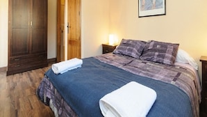 Une chambre à coucher avec un grand lit, une armoire en bois et un tableau accroché au mur.