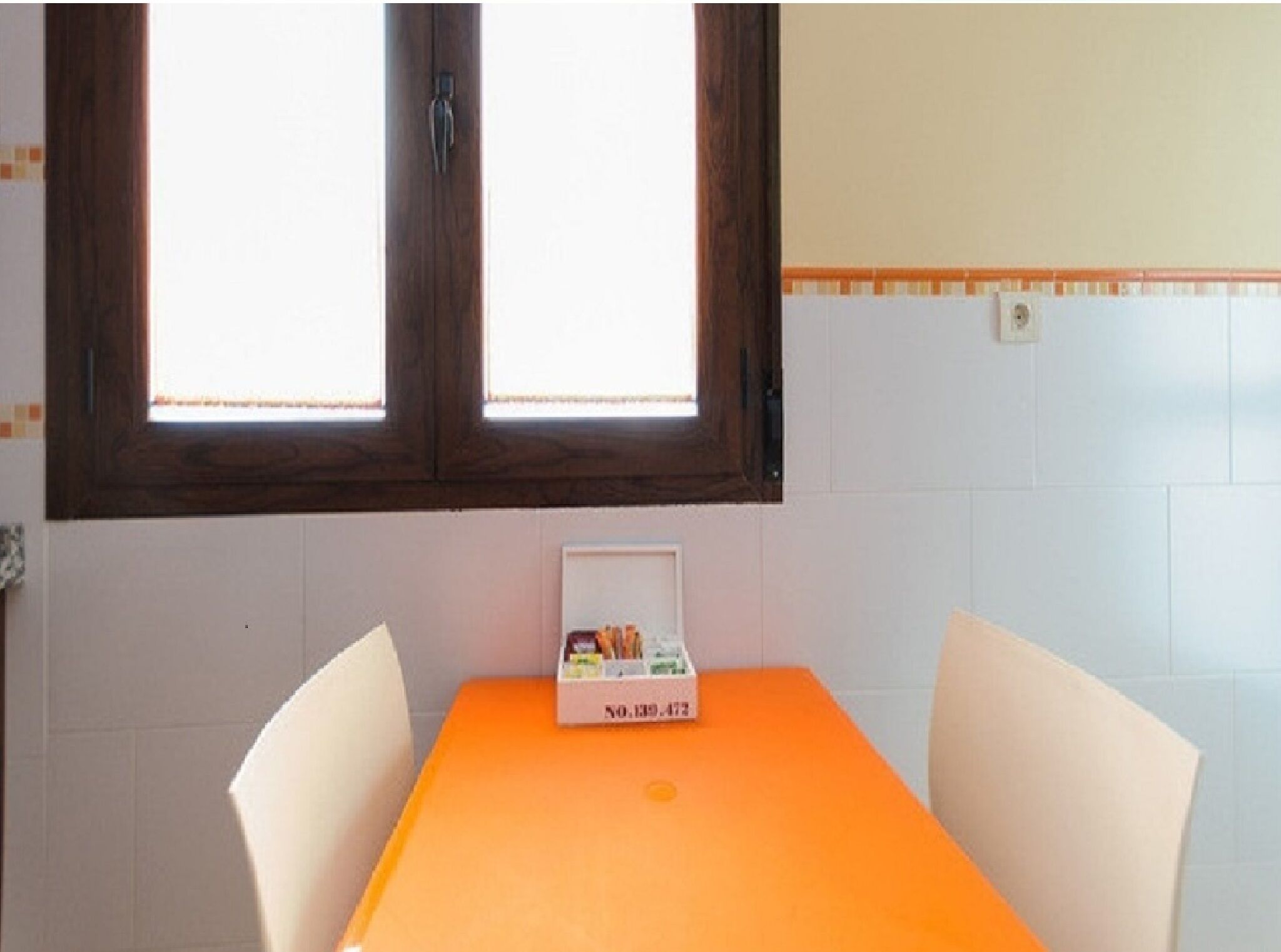 A room with a window, a table with chairs, and a box on the table.