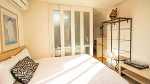 Una habitación de hotel con una cama, un armario y una estantería con objetos.