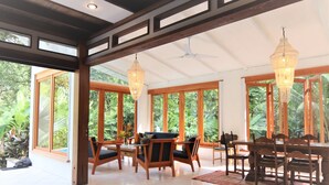 Una habitación amplia con ventanas grandes, muebles de madera y un ventilador de techo.