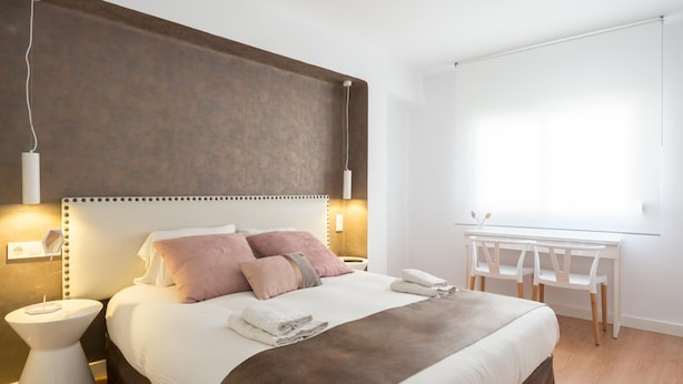 Een moderne hotelkamer met een groot bed, nachtkastjes, een bureau en een raam.