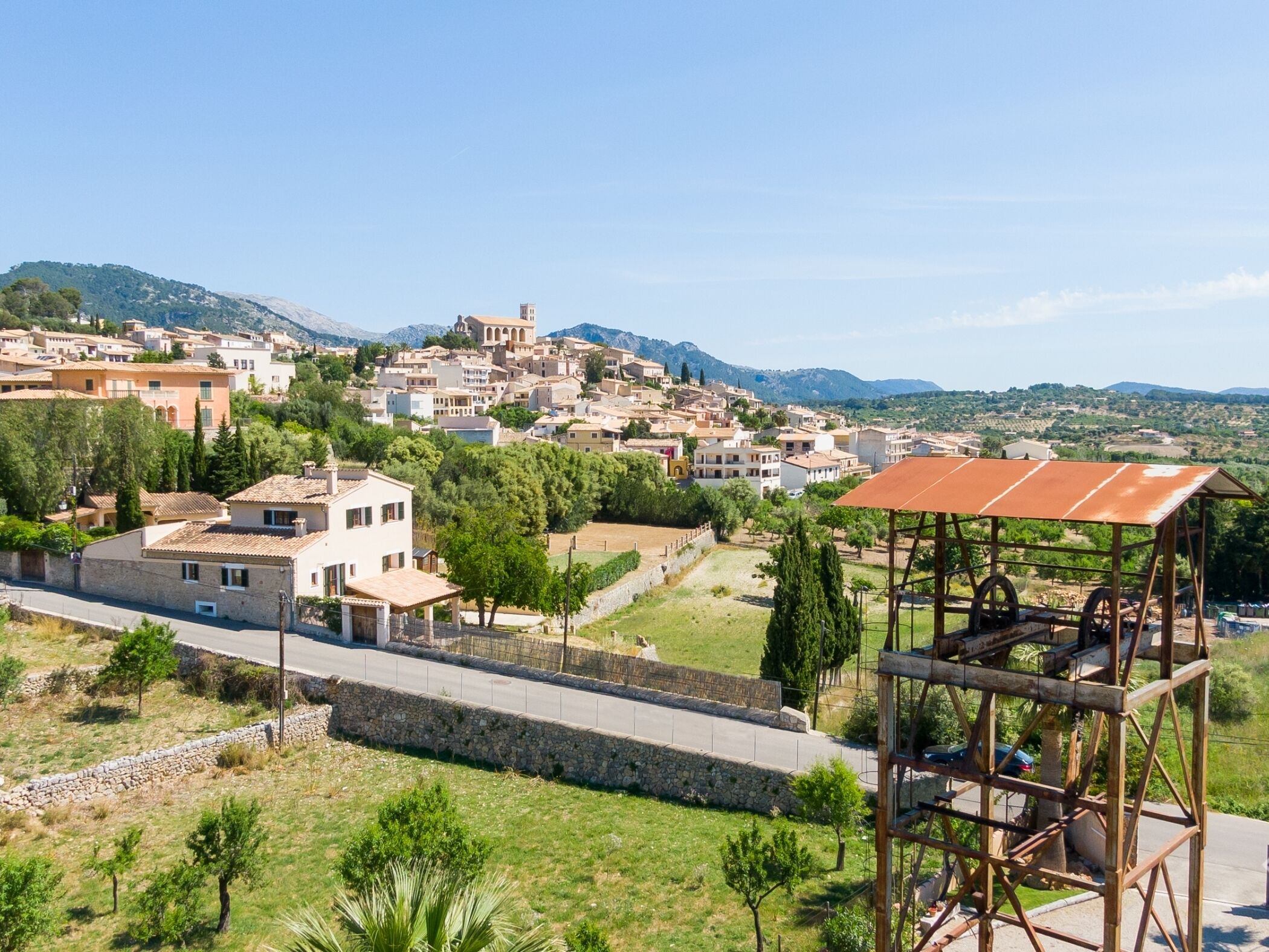 A hillside town with traditional architecture, a stone wall, and a metal structure.