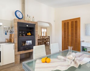 A modern kitchen with a brick backsplash, a built-in oven, and a dining area with a glass table and chairs.