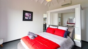 Une chambre à coucher moderne avec un grand lit, un miroir et un luminaire au plafond.