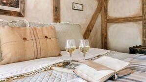 Una habitación rústica con una cama, dos copas de vino y un libro abierto.
