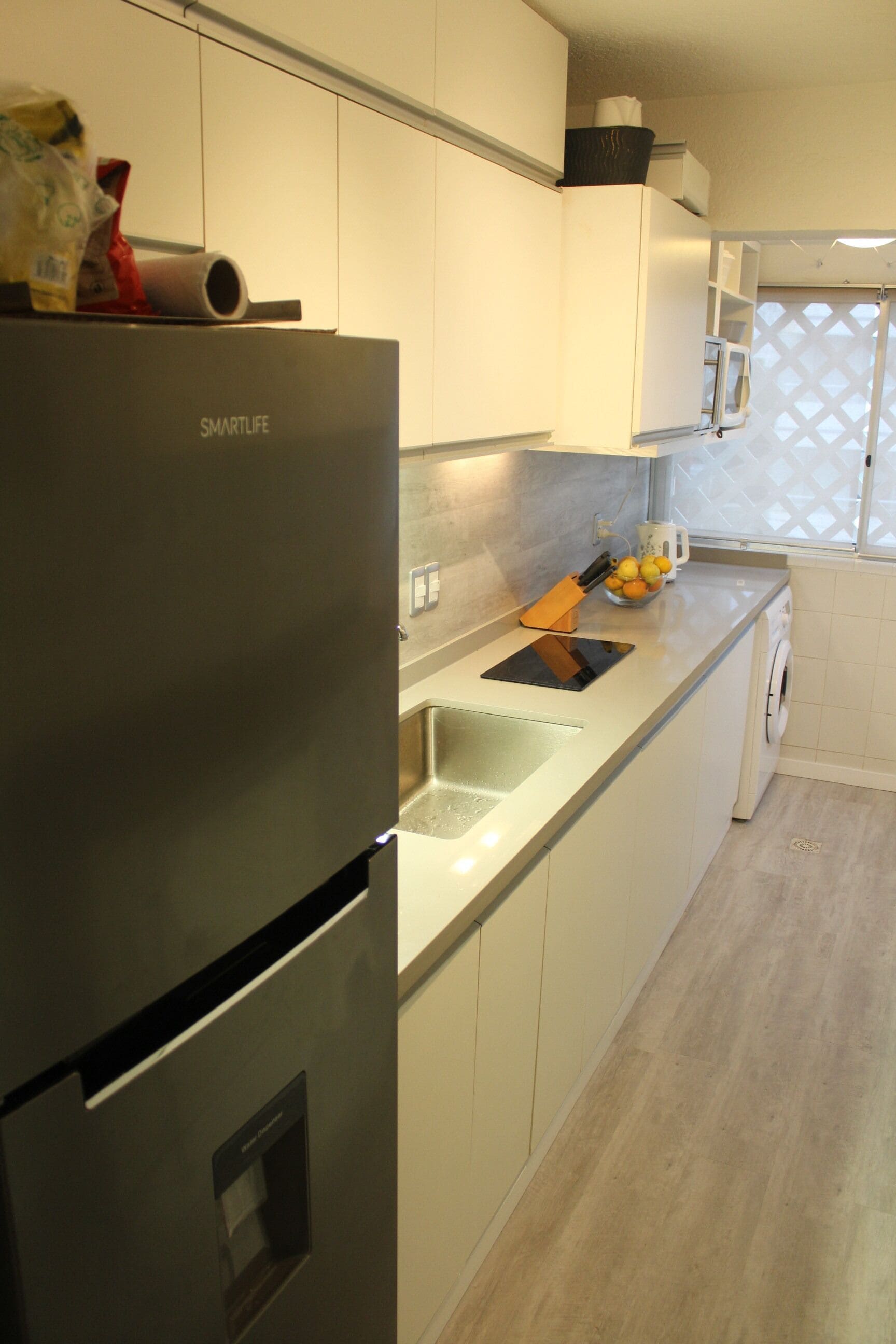 Een moderne keuken met een roestvrijstalen koelkast, witte kasten en een inbouwoven.
