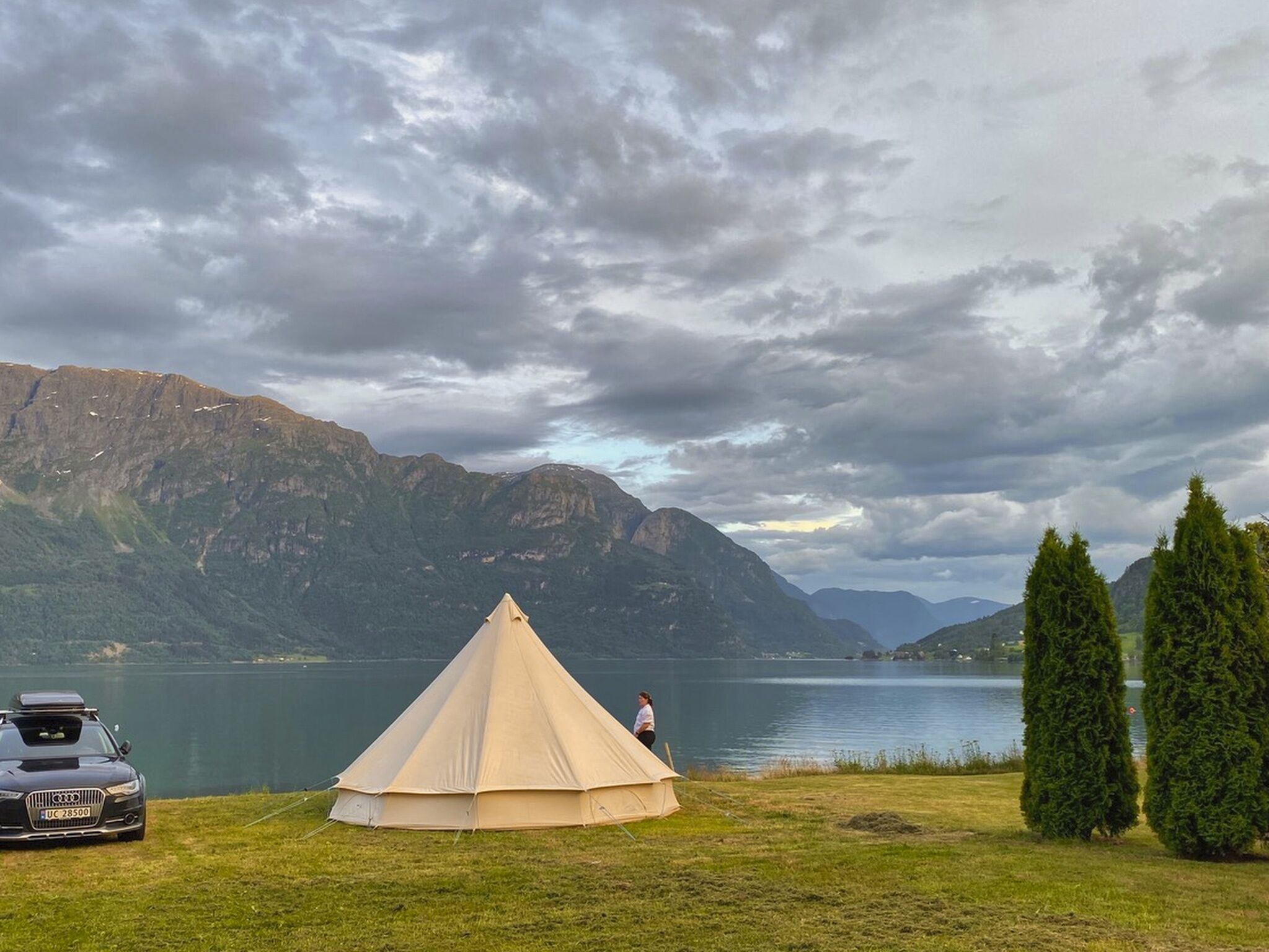 A tent set up by a lake with mountains in the background.