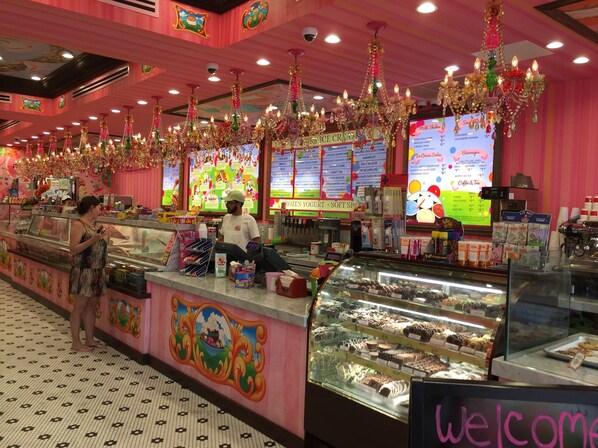 A brightly decorated ice cream shop with a variety of frozen desserts and beverages displayed in the case.
