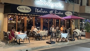 Italialainen bistro, jossa on ulkotilaterassi ja neonvalomainos.