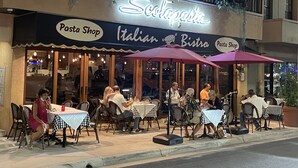 Ein italienisches Bistro mit Außenbestuhlung und einem Neonzeichen.
