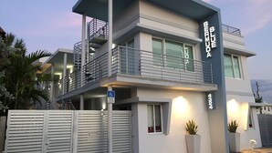 Ein modernes, zweistöckiges Gebäude mit Balkon, Rollstuhlzugang-Hinweis und einer Topfpflanze.