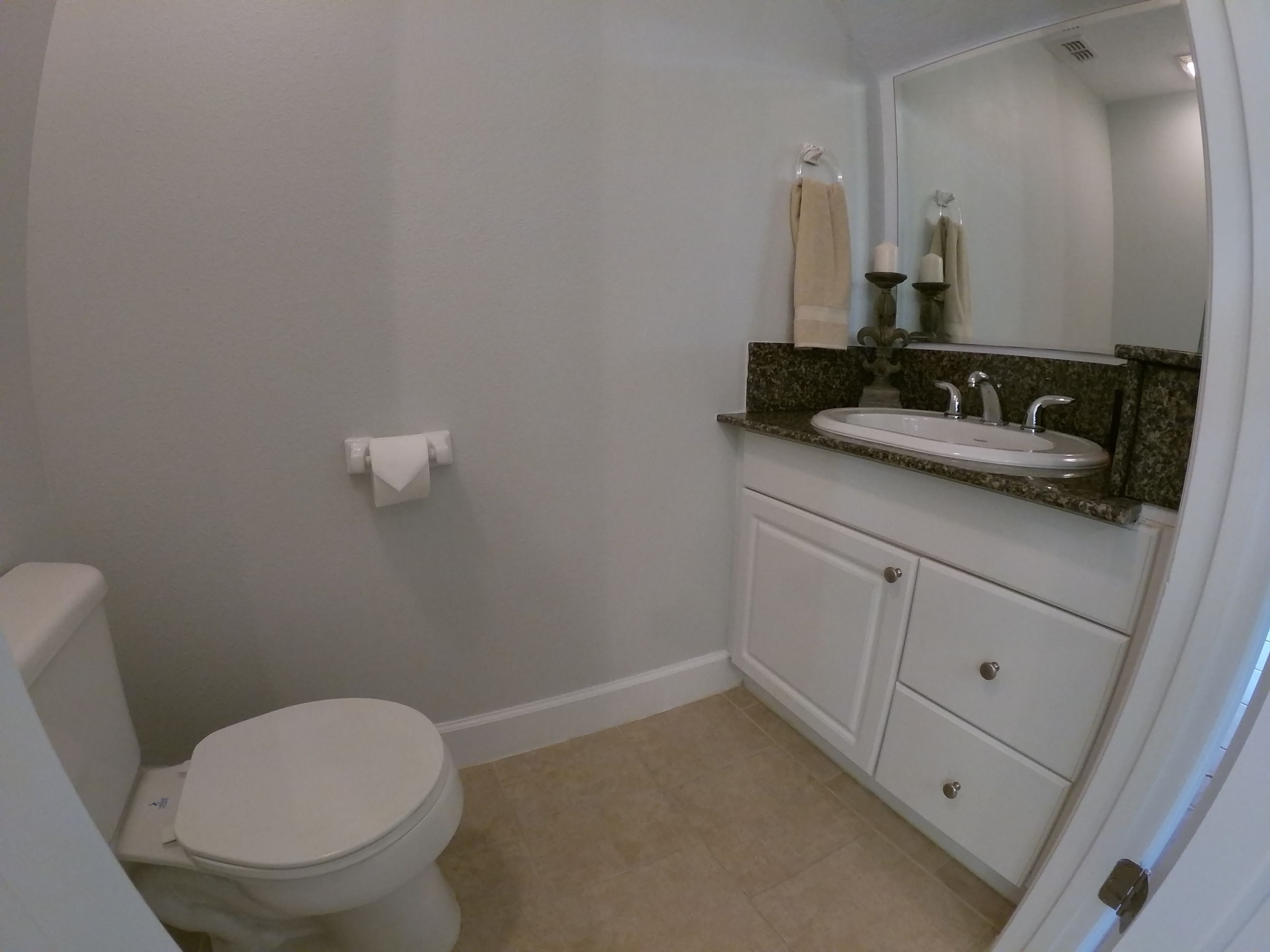 A bathroom with a toilet, sink, and mirror.