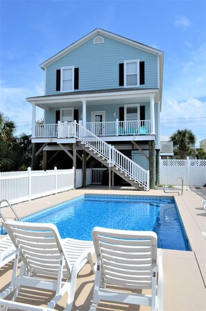 A two-story house with a pool and a covered deck area.