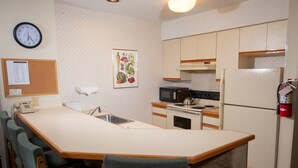 Une cuisine compacte dotée d’un îlot central, d’un four à micro-ondes, d’une cuisinière et d’un réfrigérateur.