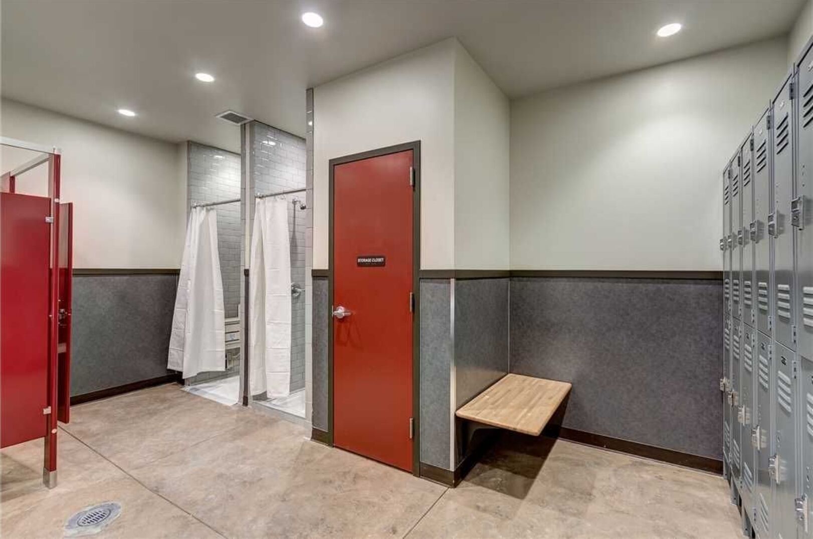 A men's restroom with a shower, a storage closet, and a bench.