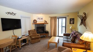 A living room with a flat-screen TV, a fireplace, a sofa, a coffee table, and a lamp. - Condo with Ski-in/Ski-Out Access, Pools and More! (Ludlow)