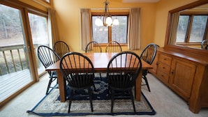 A dining room with a wooden table and chairs, large windows, and a chandelier. - Amazing Location! Charming Ski-in/Ski-out Condo (Ludlow)