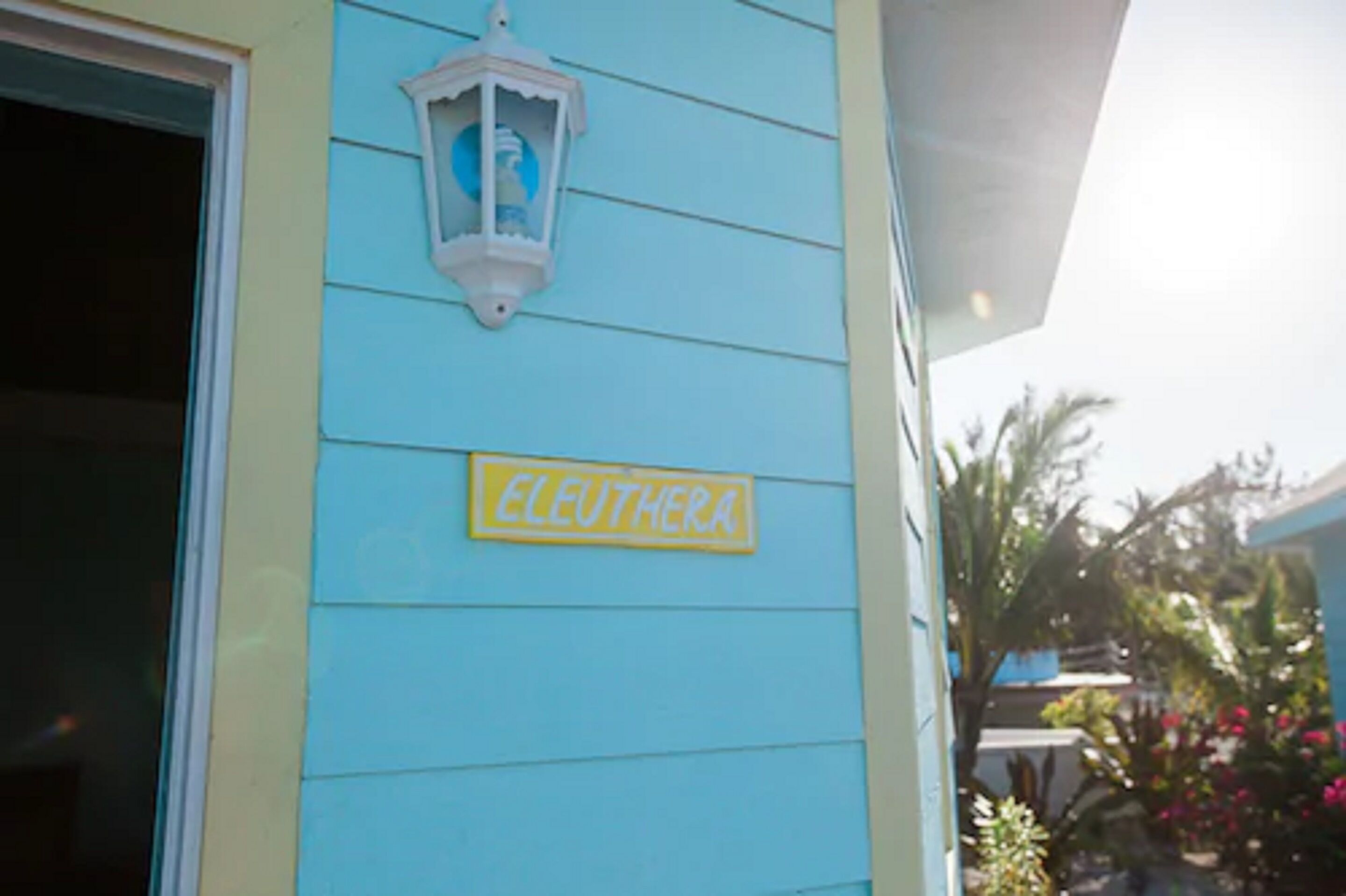 A building with a light blue exterior, a yellow sign reading "ELEUTHERA," and a white lantern.
