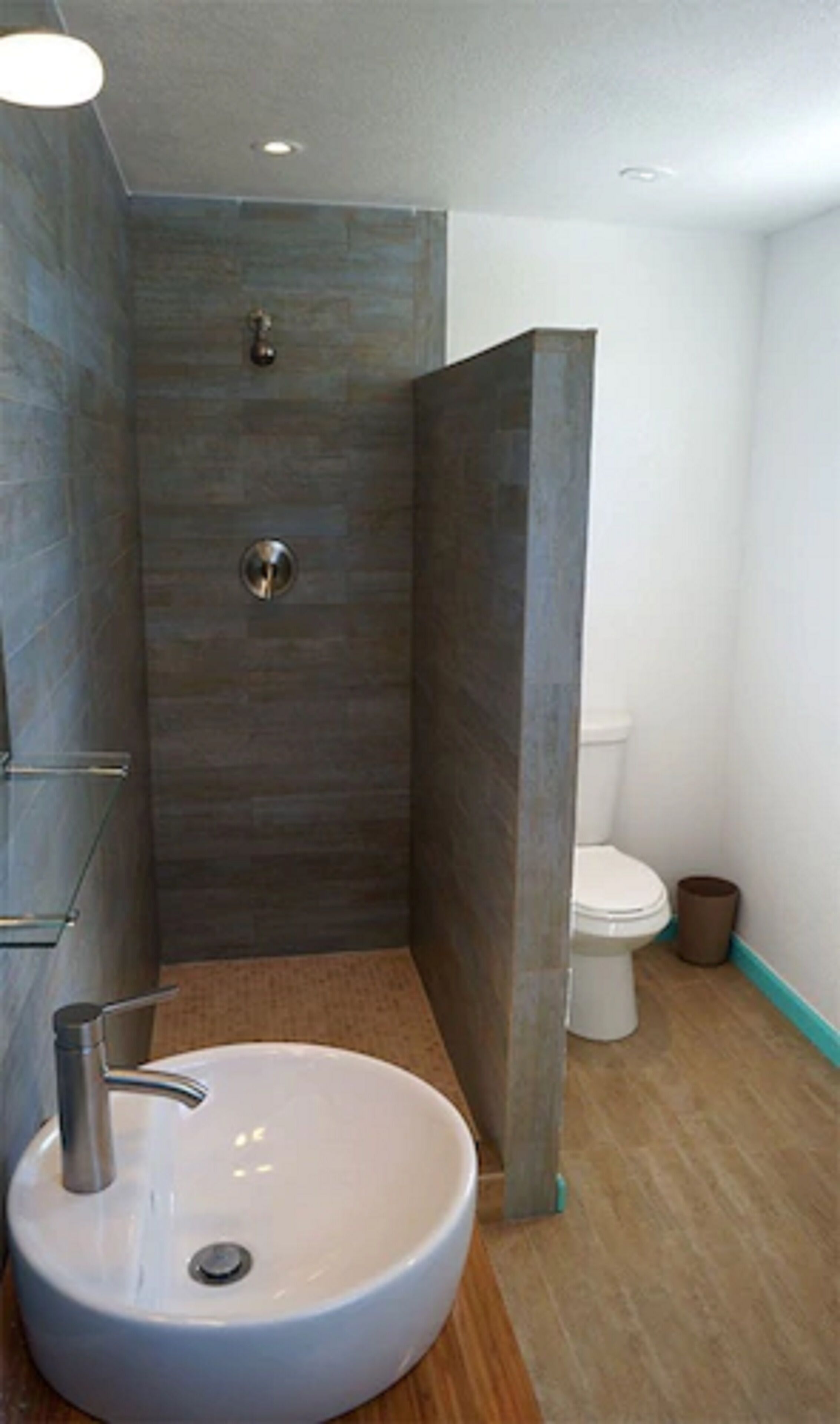 A modern bathroom with a large sink, a shower enclosure, and a toilet.