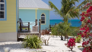 Una casa sulla spiaggia con veranda in legno, un'amaca e vista sull'oceano.