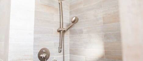 A shower with a handheld showerhead and a wall-mounted control.