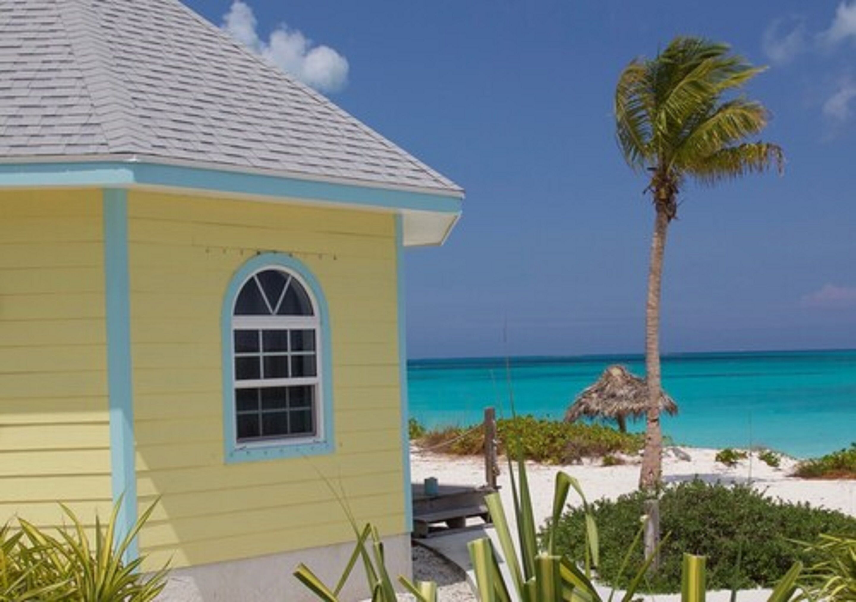 A yellow building with a blue trim, a window, and a view of the ocean.