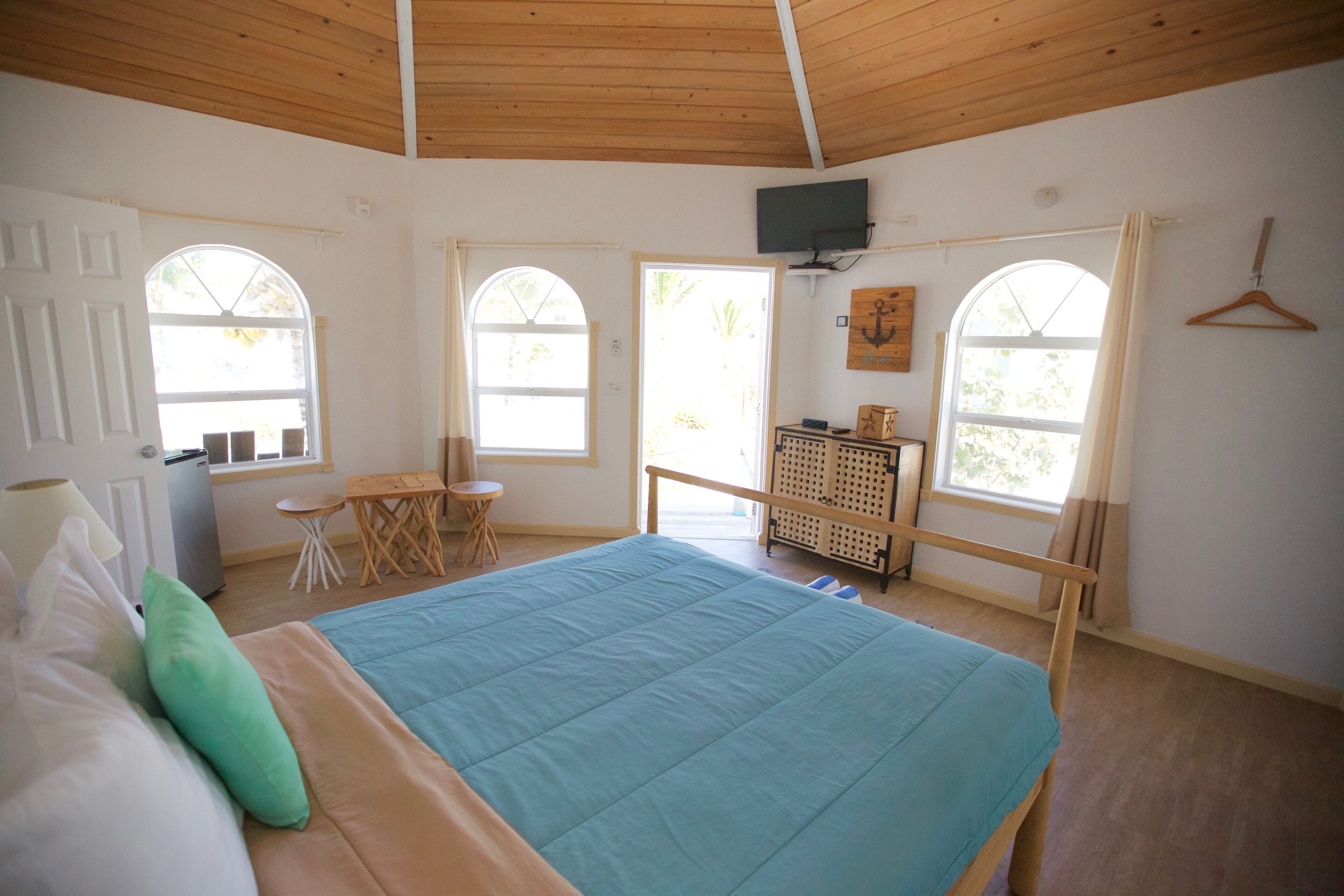 A bedroom with a bed, a desk, and a TV on the wall.