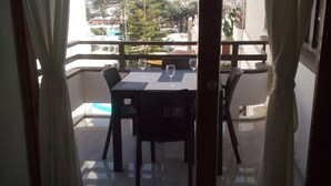 Ein Balkon mit Tisch und Stühlen, zwei Weingläsern und Blick auf einen Hafen sowie Gebäude.