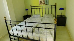 Ein Bett mit Metallgestell, zwei Nachttische und eine an der Wand befestigte Buddha-Statue.