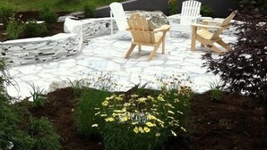 A patio with Adirondack chairs and a stone fire pit.