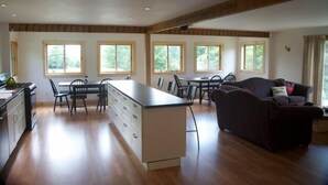 A spacious kitchen with a central island, dining area with chairs, and a sofa.