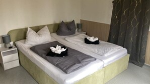 Un lit double avec deux oreillers, une table de chevet avec une lampe et un rideau à motifs ondulés.