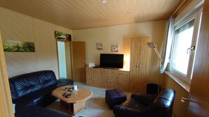Un salon avec un canapé, une table basse, un téléviseur et des meubles en bois.