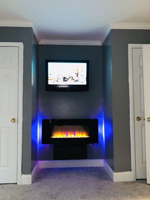 Una habitación con una televisión de pantalla plana sobre la chimenea, que tiene iluminación LED azul.