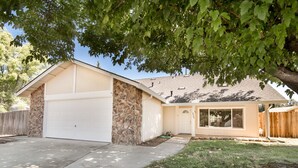 A single-story house with a garage, a stone exterior, and a covered porch. - “Spacious 5-Bedroom Retreat – Perfect for Families & Groups” (Citrus Heights)