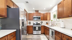 A modern kitchen with stainless steel appliances, wooden cabinets, and a white countertop. - “Spacious 5-Bedroom Retreat – Perfect for Families & Groups” (Citrus Heights)