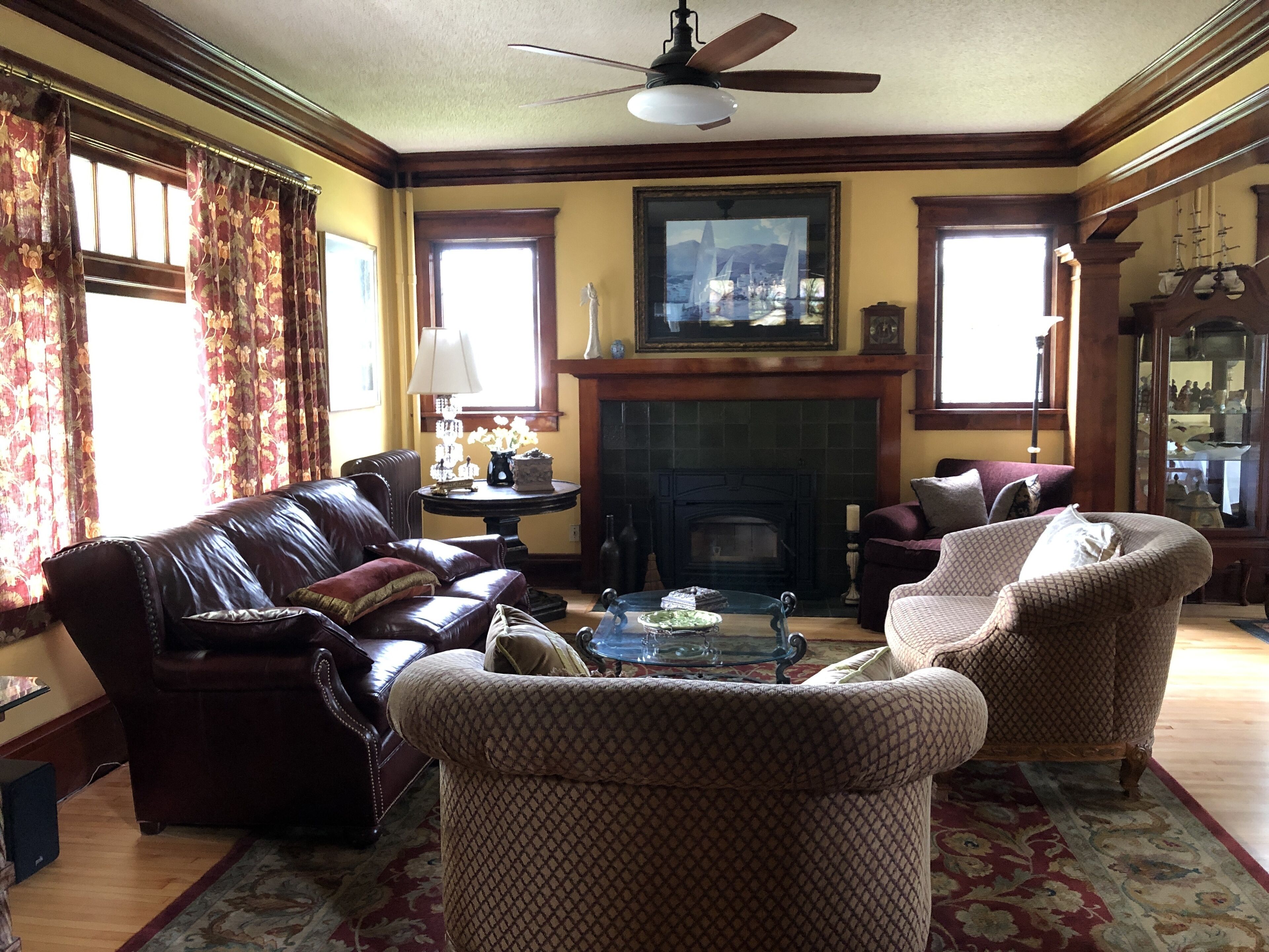A living room with a fireplace, leather sofa, patterned armchairs, and a coffee table.