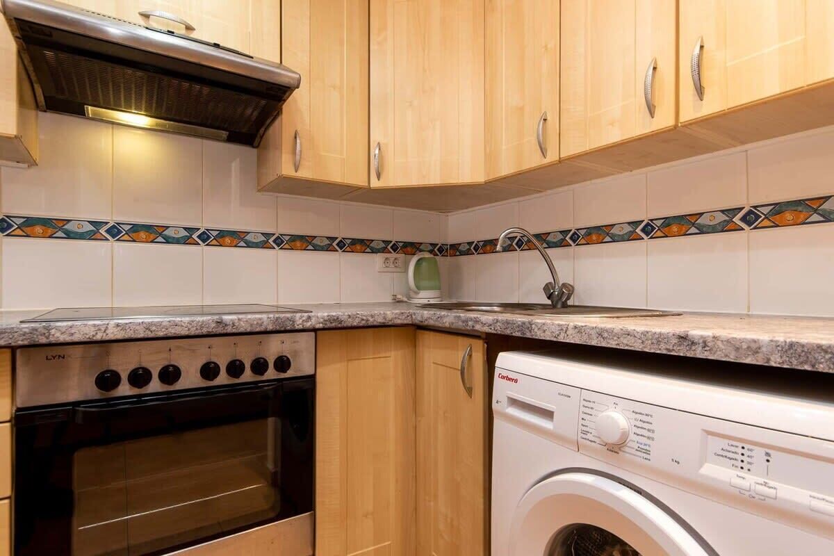 A kitchen with wooden cabinets, a granite countertop, a built-in oven, and a front-loading washing machine.