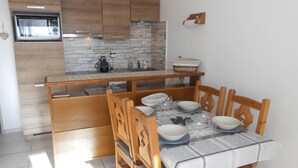 A compact kitchen with wooden cabinets, a built-in microwave, and a stone backsplash.