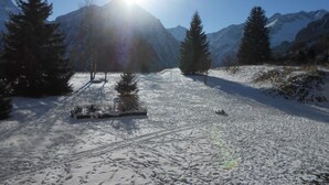 A snowy mountain landscape with a clear sky and a bright sun.