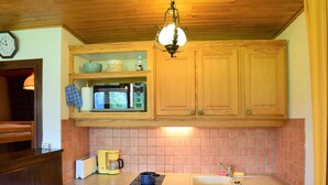 A kitchen with wooden cabinets, a microwave, a coffee maker, and a sink.