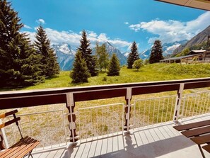 Un balcone con vista su una catena montuosa, panchine di legno e una ringhiera.