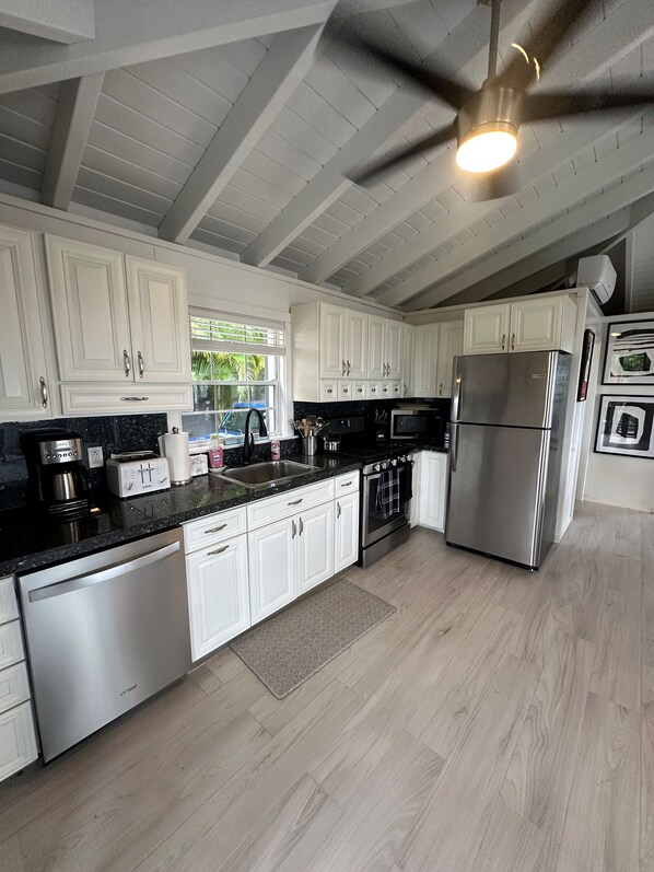 A modern kitchen with white cabinets, stainless steel appliances, and a black countertop. - 2 BR/2 BA CORAL BAY. REFRESHED INSIDE & AC THROUGHOUT! NEW POOL! NEW GENERATOR! (St John)