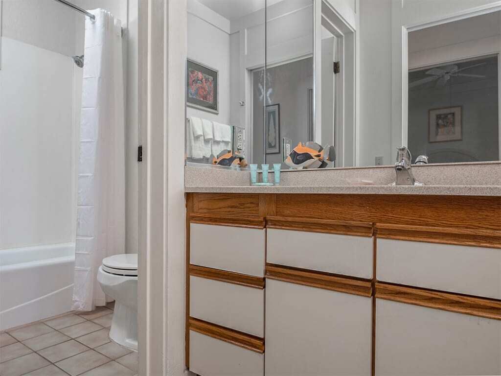 A bathroom with a bathtub, toilet, and a large mirror.