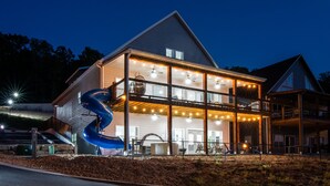 A two-story building with a large slide and outdoor seating area. - Twisty slide, Lake view, Hot tub, Indoor pool, Fire pit | Skye Retreat (Branson)